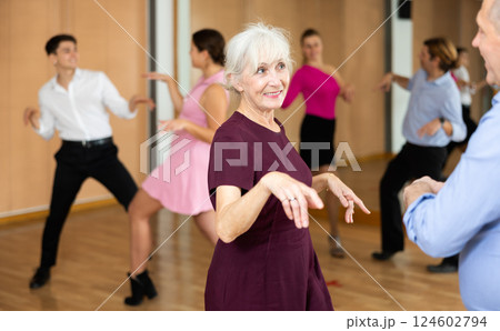 Cheerful elderly female dancer practicing ballroom dances in ballroom Cheerful elderly female dancer practicing ballroom dances in ballroom 124602794