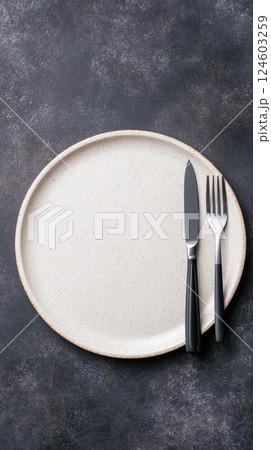 Empty plate with knife and fork on dark background 124603259