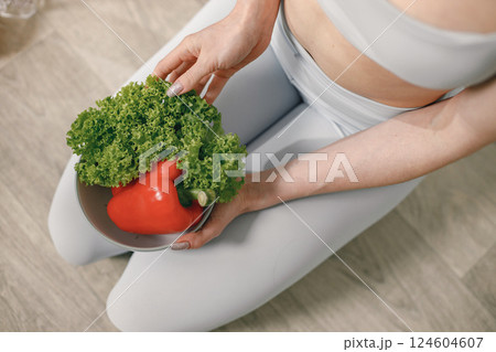 Fit woman with lots of healthy fresh food at home. Cropped view of woman wearing grey leggins. Concept of losing weight, sports and healthy eating. 124604607