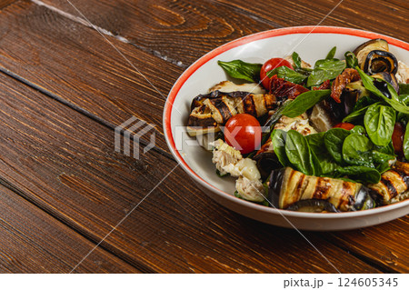 Grilled eggplant and tomato salad with fresh basil on wooden table 124605345