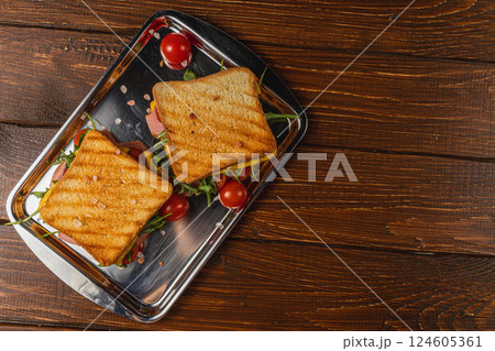Delicious grilled cheese and ham sandwich served with fresh tomatoes Delicious grilled cheese and ham sandwich served with fresh tomatoes 124605361