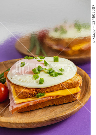 Delicious breakfast sandwich with egg, cheese, and ham on wooden plate 124605387