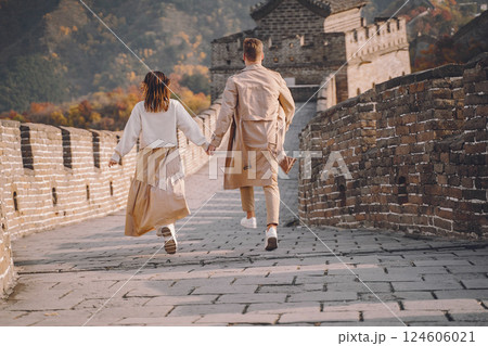 beautiful young couple running and jumping at the Great Wall of China. Newly married couple on their honemoon to Great Wall near Beijing China. Stylish couple exploring one of the wonders of the world 124606021