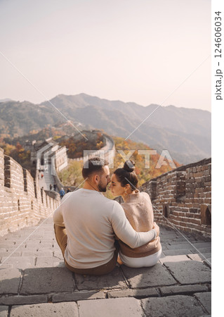 beautiful young couple sitting down and showing affection at the Great Wall of China. Newly married couple on their honemoon to Great Wall near Beijing China. Stylish couple exploring one of the beautiful young couple sitting down and showing affection at the Great Wall of China. Newly married couple on their honemoon to Great Wall near Beijing China. Stylish couple exploring one of the 124606034