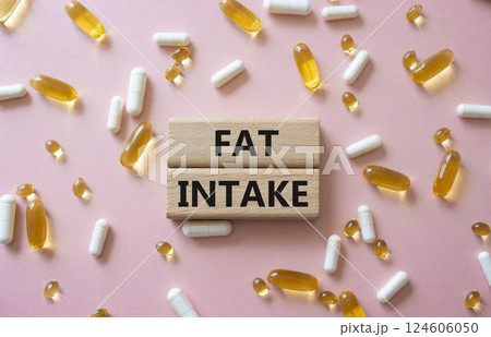 Fat Intake symbol. Concept word Fat Intake on wooden blocks. Beautiful pink background with pills. Medicine and Fat Intake concept. Copy space 124606050