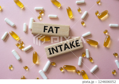 Fat Intake symbol. Concept word Fat Intake on wooden blocks. Beautiful pink background with pills. Medicine and Fat Intake concept. Copy space Fat Intake symbol. Concept word Fat Intake on wooden blocks. Beautiful pink background with pills. Medicine and Fat Intake concept. Copy space 124606052