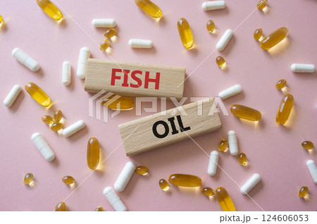 Fish Oil symbol. Concept word Fish Oil on wooden blocks. Beautiful pink background with pills. Medicine and Fish Oil concept. Copy space Fish Oil symbol. Concept word Fish Oil on wooden blocks. Beautiful pink background with pills. Medicine and Fish Oil concept. Copy space 124606053