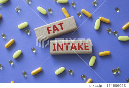 Fat Intake symbol. Concept word Fat Intake on wooden blocks. Beautiful purple background with pills. Medicine and Fat Intake concept. Copy space 124606068