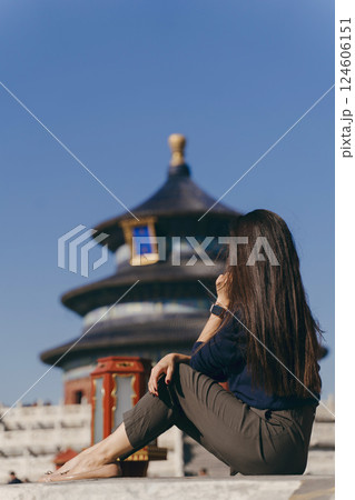 brunette girl sitting on the steps by temple of heaven in China. Brunette girl enjoying chinese architecture while sitting on the steps and relaxing. Caucasian tourist taking a break from exploring brunette girl sitting on the steps by temple of heaven in China. Brunette girl enjoying chinese architecture while sitting on the steps and relaxing. Caucasian tourist taking a break from exploring 124606151