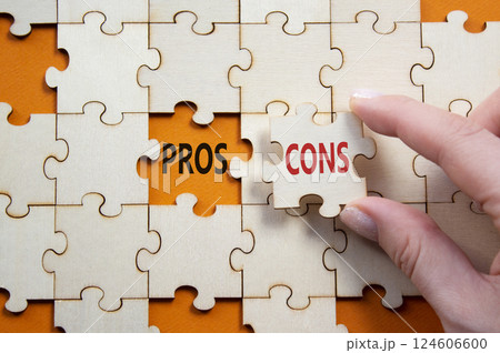 Pros vs Cons symbol. Concept word Pros vs Cons on wooden puzzle. Businessman hand. Beautiful orange background. Business and Pros vs Cons concept. Copy space 124606600