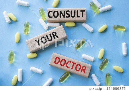 Consult Your Doctor symbol. Concept word Consult Your Doctor on wooden blocks. Beautiful blue background with pills. Medicine and Consult Your Doctor concept. Copy space 124606875