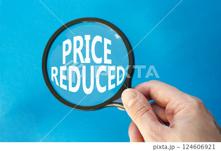 Price reduced symbol. Magnifying Glass with Concept word Price reduced. Beautiful blue background. Businessman hand. Business and Price reduced concept. Copy space 124606921