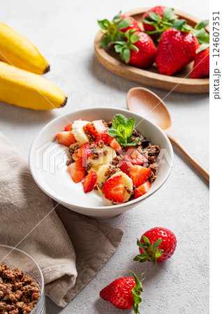 Natural Greek yogurt with homemade chocolate granola, strawberries and banana in a bowl Natural Greek yogurt with homemade chocolate granola, strawberries and banana in a bowl 124607351