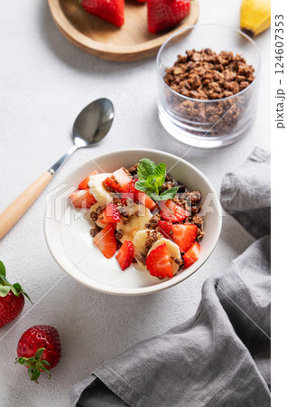 Natural Greek yogurt with homemade chocolate granola, strawberries and banana in a bowl 124607353