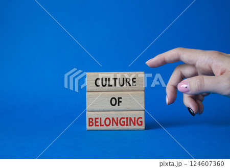 Culture of Belonging symbol. Wooden blocks with words Culture of Belonging. Businessman hand. Beautiful blue background. Business and Culture of Belonging concept. Copy space. 124607360
