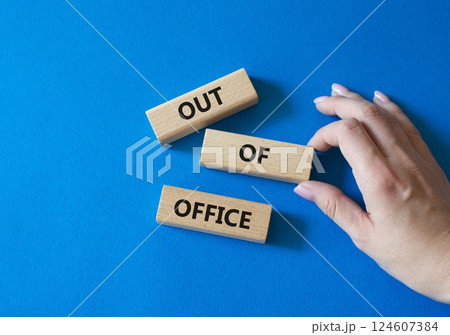Out of Office symbol. Concept words Out of Office on wooden blocks. Businessman hand. Beautiful blue background. Business and Out of Office concept. Copy space Out of Office symbol. Concept words Out of Office on wooden blocks. Businessman hand. Beautiful blue background. Business and Out of Office concept. Copy space 124607384