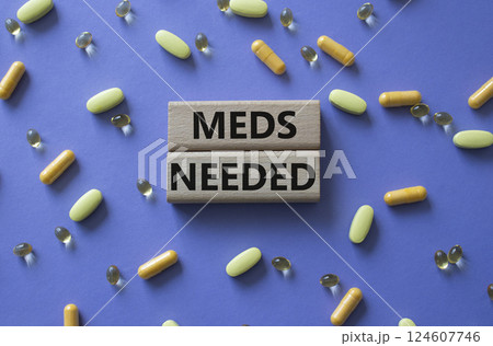 Meds Needed symbol. Concept word Meds Needed on wooden blocks. Beautiful purple background with pills. Medicine and Meds Needed concept. Copy space 124607746
