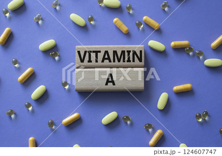 Vitamin A symbol. Concept word Vitamin A on wooden blocks. Beautiful purple background with pills. Medicine and Vitamin A concept. Copy space 124607747
