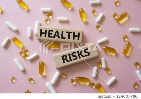 Health Risks symbol. Concept word Health Risks on wooden blocks. Beautiful pink background with pills. Medicine and Health Risks concept. Copy space 124607780
