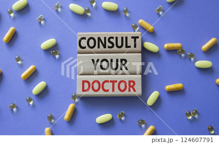 Consult Your Doctor symbol. Concept word Consult Your Doctor on wooden blocks. Beautiful purple background with pills. Medicine and Consult Your Doctor concept. Copy space Consult Your Doctor symbol. Concept word Consult Your Doctor on wooden blocks. Beautiful purple background with pills. Medicine and Consult Your Doctor concept. Copy space 124607791