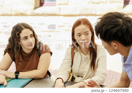 屋外のキャンパスで談笑する大学生の男女 124607980