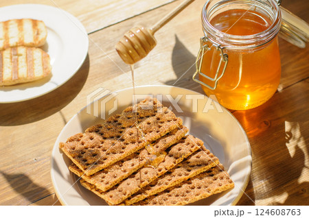Crispy Wafers Stacked on a Plate With Honey Being Drizzled Over Them, Creating an Inviting and Tasty Atmosphere on a Sunny Day 124608763