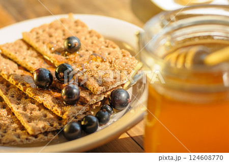 A Plate of Crunchy Crackers is Elegantly Presented With Fresh Berries and Honey, Bathed in Gentle Sunlight A Plate of Crunchy Crackers is Elegantly Presented With Fresh Berries and Honey, Bathed in Gentle Sunlight 124608770