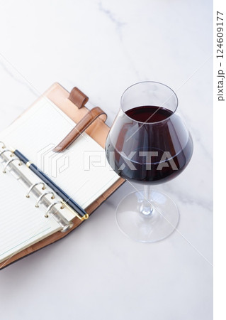 赤ワインを飲みながら、リング式のシステム手帳に日記をつけているイメージ写真 赤ワインを飲みながら、リング式のシステム手帳に日記をつけているイメージ写真 124609177