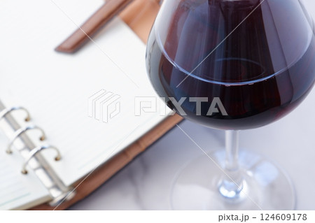 赤ワインを飲みながら、リング式のシステム手帳に日記をつけているイメージ写真 124609178