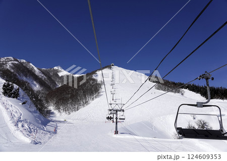 快晴のスキー場 頂上へ続くリフトと真っ白なゲレンデ 124609353