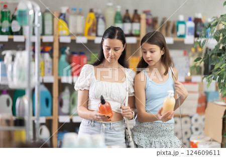 Woman with preteen daughter choosing liquid soap in store 124609611