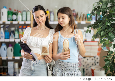 Woman with daughter choosing hairbrush in store 124609725