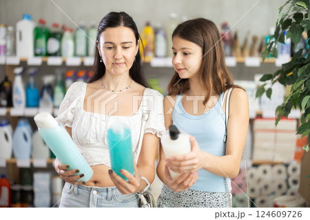 Woman with teen daughter choosing shampoo in hygiene store 124609726