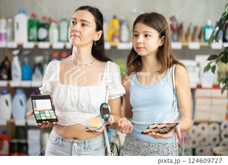Mom with teen girl view trademark sign on label, pick eco friendly face cosmetic pallet 124609727