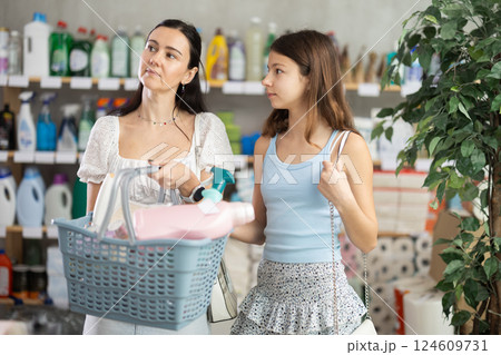 Woman with daughter choosing household chemicals in store 124609731