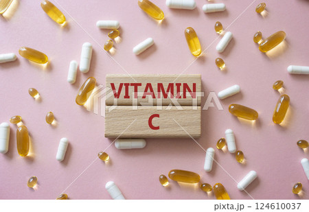 Vitamin C symbol. Concept word Vitamin C on wooden blocks. Beautiful pink background with pills. Medicine and Vitamin C concept. Copy space 124610037
