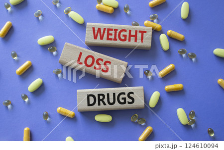 Medicine symbol. Concept words Weight Loss Drugs on wooden blocks. Beautiful purple background with pills. Medicine concept and Weight Loss Drugs. Copy space 124610094