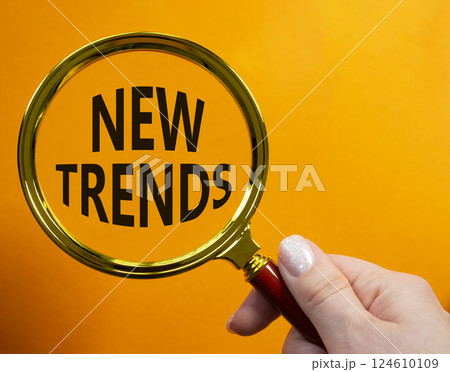 New Trends symbol. Magnifying glass with words New Trends. Businessman hand. Beautiful orange background. Business and New Trends concept. Copy space. New Trends symbol. Magnifying glass with words New Trends. Businessman hand. Beautiful orange background. Business and New Trends concept. Copy space. 124610109