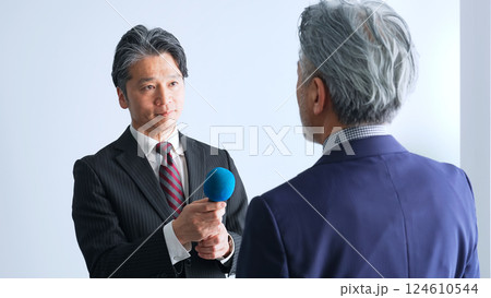 マイクを持ってインタビューするミドルエイジ男性レポーター マイクを持ってインタビューするミドルエイジ男性レポーター 124610544