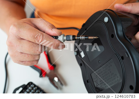 A person with dry skin repairs a broken appliance using a small screwdriver 124610783
