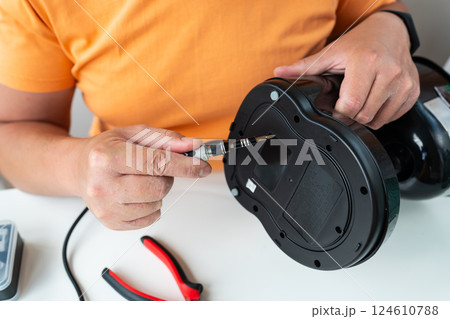 A person carefully repairs a broken appliance using a small screwdriver, demonstrating DIY home repair 124610788