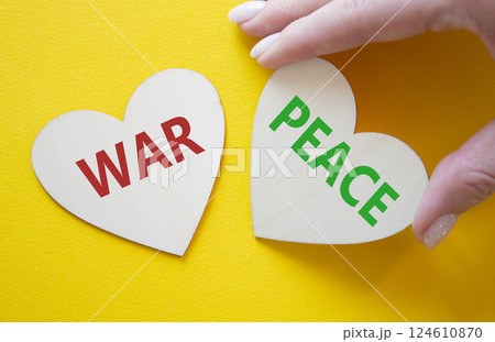 War or Peace symbol. Concept word War or Peace on wooden hearts. Businessman hand. Beautiful yellow background. Business and War or Peace concept. Copy space 124610870