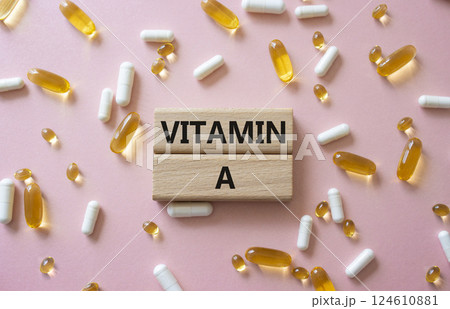 Vitamin A symbol. Concept word Vitamin A on wooden blocks. Beautiful pink background with pills. Medicine and Vitamin A concept. Copy space 124610881