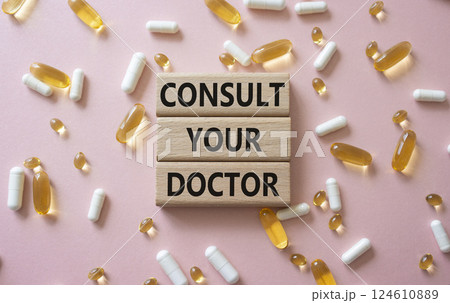 Consult Your Doctor symbol. Concept word Consult Your Doctor on wooden blocks. Beautiful pink background with pills. Medicine and Consult Your Doctor concept. Copy space Consult Your Doctor symbol. Concept word Consult Your Doctor on wooden blocks. Beautiful pink background with pills. Medicine and Consult Your Doctor concept. Copy space 124610889