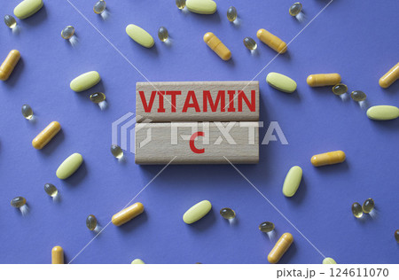 Vitamin C symbol. Concept word Vitamin C on wooden blocks. Beautiful purple background with pills. Medicine and Vitamin C concept. Copy space 124611070