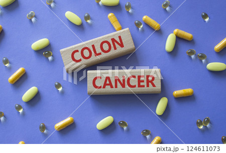 Colon Cancer symbol. Concept word Colon Cancer on wooden blocks. Beautiful purple background with pills. Medicine and Colon Cancer concept. Copy space 124611073