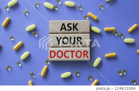 Ask Your Doctor symbol. Concept word Ask Your Doctor on wooden blocks. Beautiful purple background with pills. Medicine and Ask Your Doctor concept. Copy space 124611084