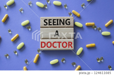Seeing a Doctor symbol. Concept word Seeing a Doctor on wooden blocks. Beautiful purple background with pills. Medicine and Seeing a Doctor concept. Copy space Seeing a Doctor symbol. Concept word Seeing a Doctor on wooden blocks. Beautiful purple background with pills. Medicine and Seeing a Doctor concept. Copy space 124611085
