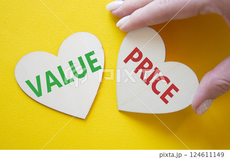Price and Value symbol. Concept word Price and Value on wooden hearts. Businessman hand. Beautiful yellow background. Business and Price and Value concept. Copy space 124611149
