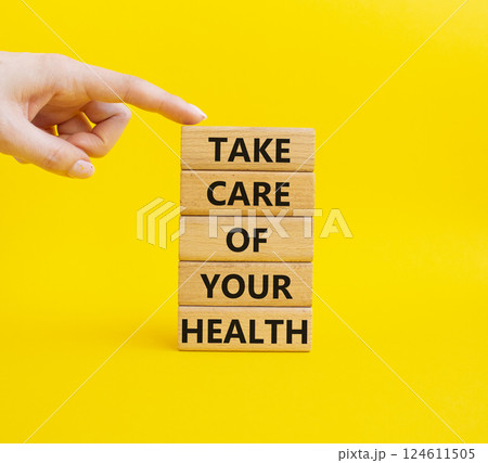 Health symbol. Wooden blocks with words Take Care of your Health. Businessman hand. Beautiful yellow background. Health concept. Copy space. Health symbol. Wooden blocks with words Take Care of your Health. Businessman hand. Beautiful yellow background. Health concept. Copy space. 124611505